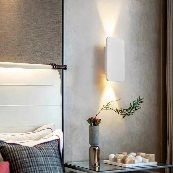 Brushed Gold/Black Double Head Wall Light illuminating a modern bedroom wall with stylish minimalism.