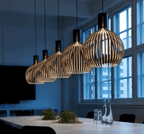 Nordic Retro Modern Wood Cage Pendant lighting hanging over a dining table, showcasing elegant and contemporary design.