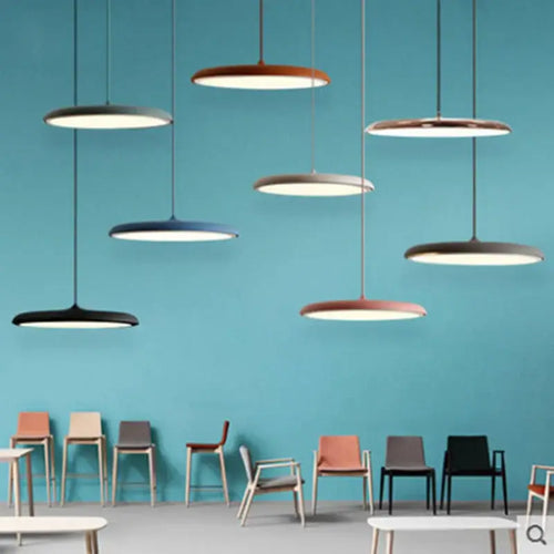 Minimalist Metal Hanging Lamp in various colors suspended in a modern space with stylish chairs.