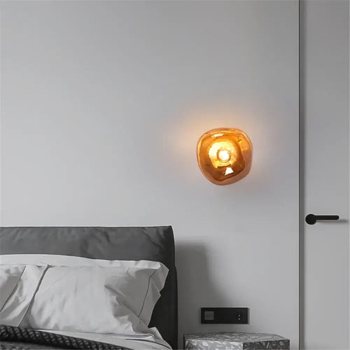 Lava Glass Wall Lamp illuminated on the wall next to a stylish bed, enhancing bedroom decor and ambiance.