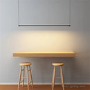 Super Simple Line Lighting | Modern LED Pendant Lamp illuminating a minimalistic table and stools in a contemporary setting.
