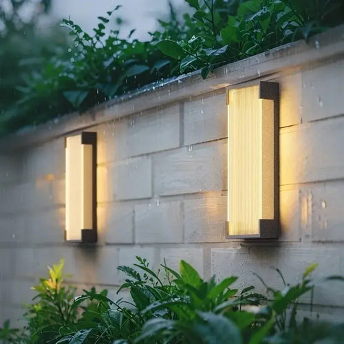 Modern Stainless Steel Wall Light illuminating a garden wall with lush plants and soft outdoor lighting.