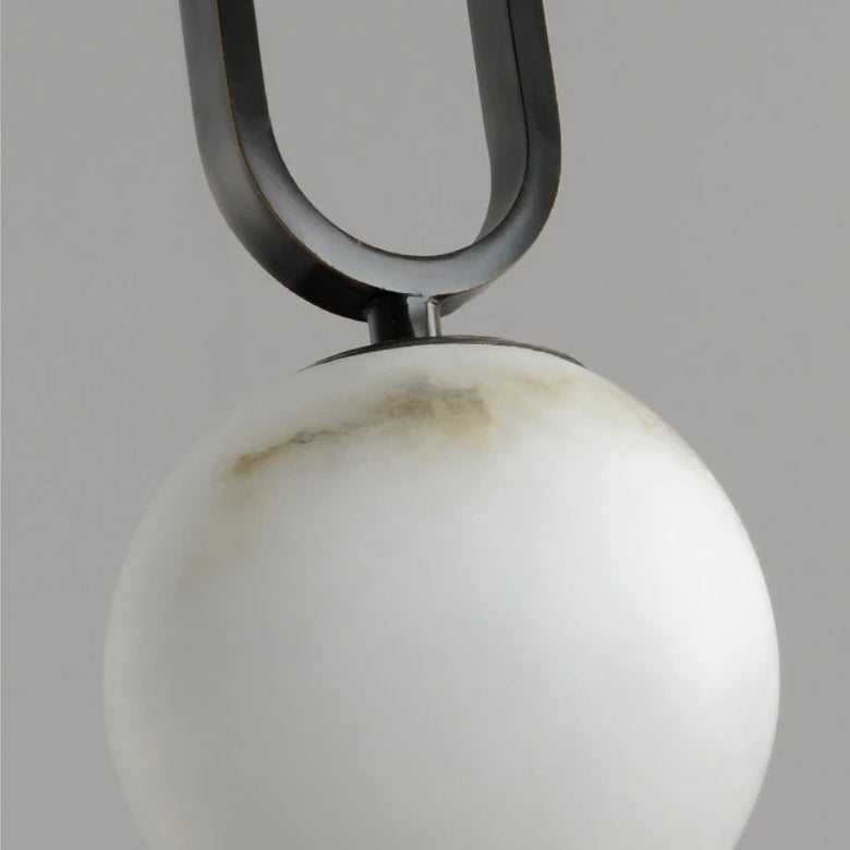 Close-up of a pendant with a marble white sphere and black U-shaped metal arm on a gray background