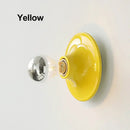 80s revival wall light in vibrant yellow with UFO-shaped base and silver top light bulb.