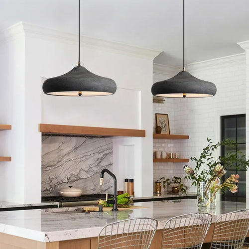 Modern kitchen with pendant lights, marble backsplash, and white cabinets.