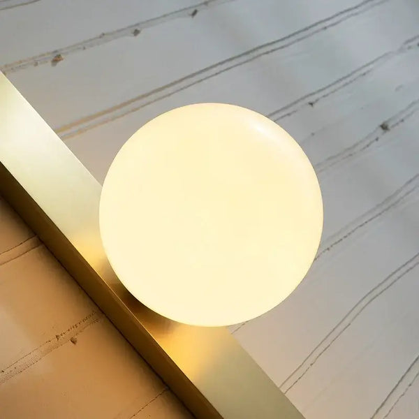 Contemporary Golden Wall Lamp with Glass Ball illuminating a stylish living space.