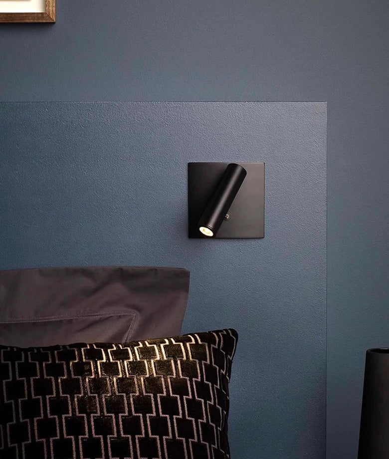 Hero Black wall-mounted light fixture on a blue wall with pillows in the foreground.