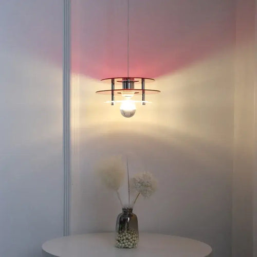 Space Age Acrylic Colorful Pendant Light hanging above a table, casting vibrant colored shadows on the wall.