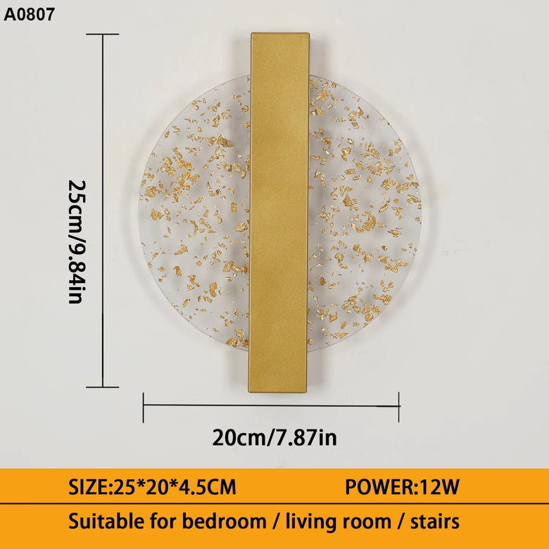 A wall-mounted circular light fixture with a white marble-look face speckled with gold leaf and a vertical gold metal bar. The image includes dimension markings showing a height of 25cm (9.