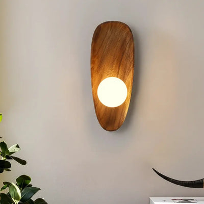Hero Wooden walnut wall sconce with a light bulb on a plain wall, next to a plant.