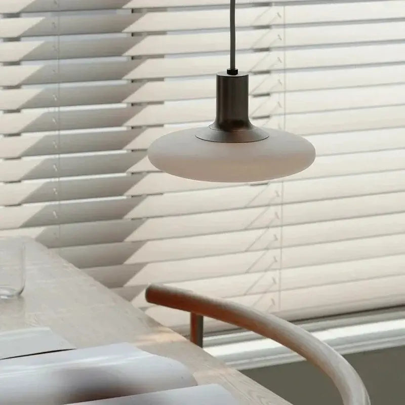 Nordic UFO LED Pendant Light – Minimalist Floating Disc Ceiling Lamp hanging above a dining table with blinds in background.