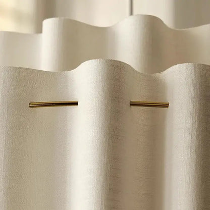 Close-up of a white curtain with a gold rod, showcasing subtle texture and elegant design.