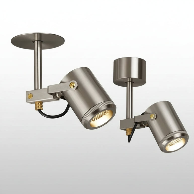 Hero Two modern ceiling-mounted spotlight fixtures with brushed silver metal shades and adjustable heads, shown against a gray ceiling and wall.