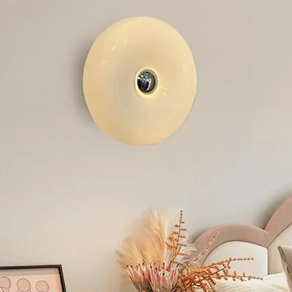 Glass Donut Wall Lamp elegantly illuminating a modern living space with cream glass shade.
