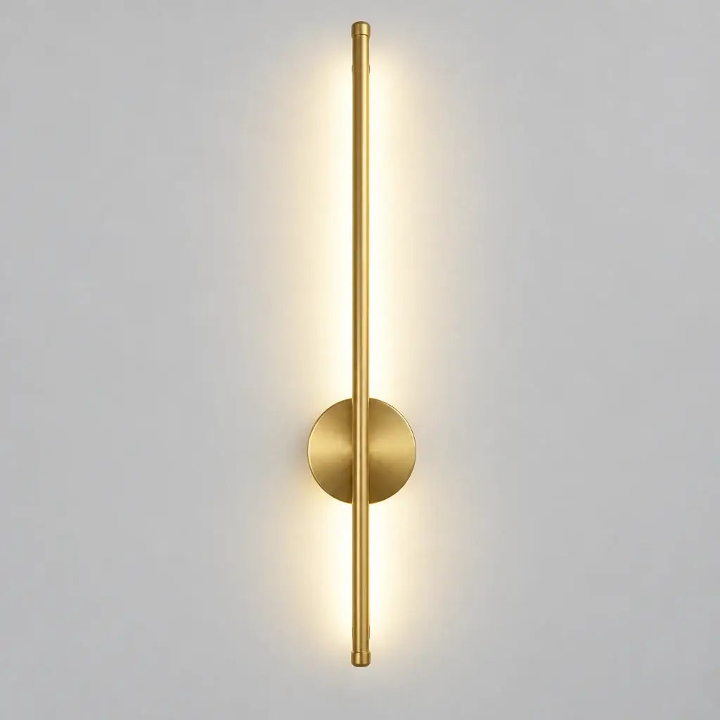  Hero Magnetic Wall Lamp / wall sconce light fixture in brushed gold/brass finish with a circular backplate and vertical light bar, shown lit on a light gray wall. 