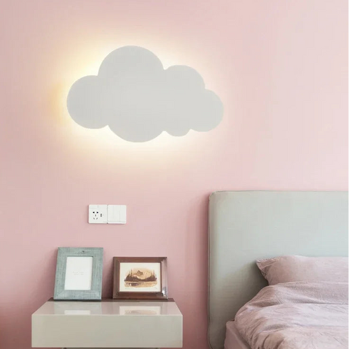 Cloud-shaped wall light fixture on a pink wall above a bed.