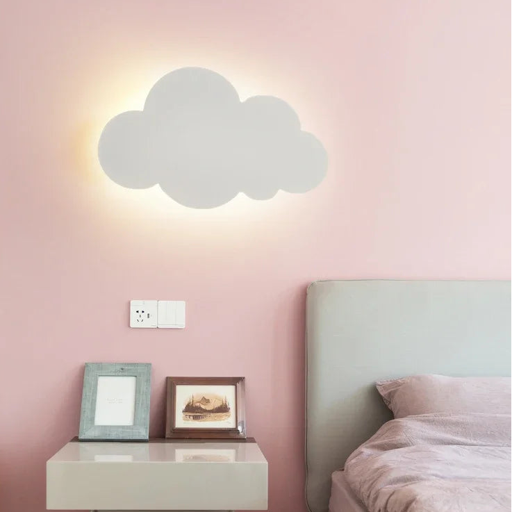 Cloud-shaped wall light fixture on a pink wall above a bed.