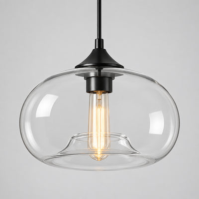 Hero A pendant light with a clear glass dome shade and a black metal ceiling mount and cord, shown against a neutral interior wall.