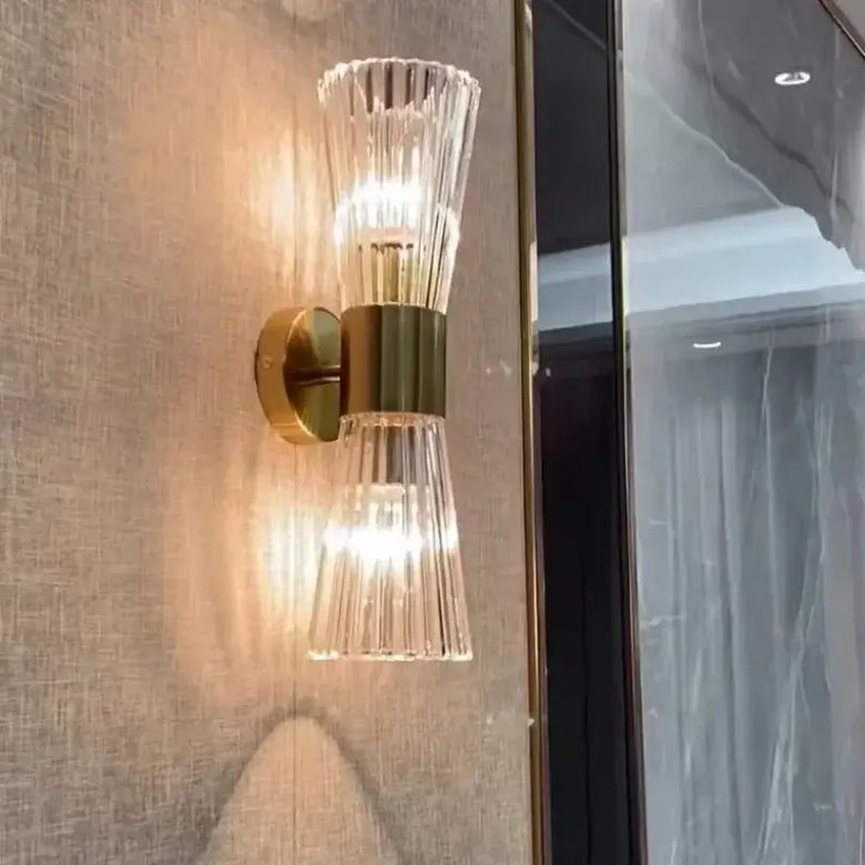 Unique Collection of Art Deco Sconces featuring elegant clear glass and gold accents on a textured wall.