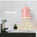 Nordic Bell Bedside Wall Lamp in pink with adjustable shade on a black marble table, showcasing magazines and cacti.