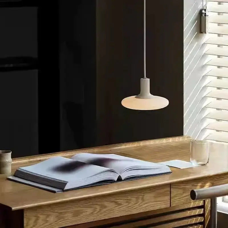 Nordic UFO LED Pendant Light – Minimalist Floating Disc Ceiling Lamp above a wooden table with an open book.