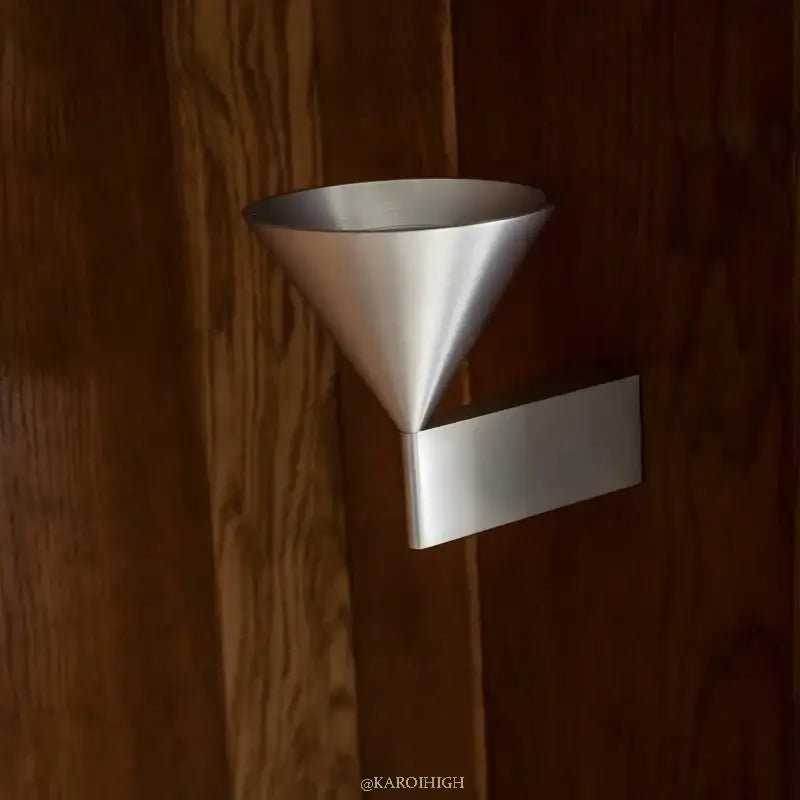 Metallic funnel-shaped object attached to a wooden surface