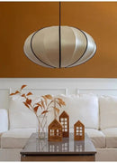 Zen Silk Pendant Light Mid Century Fabric Lantern illuminating a stylish living room with decorative elements.
