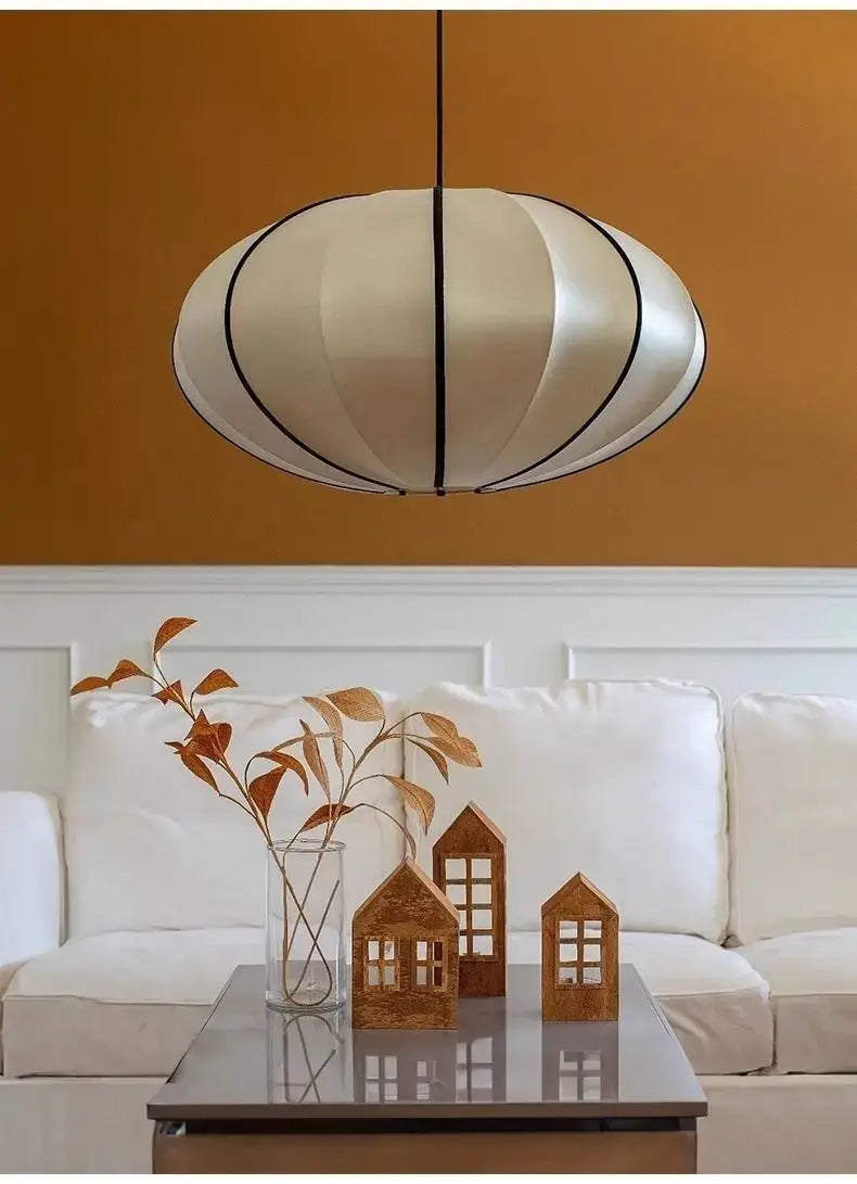 Zen Silk Pendant Light Mid Century Fabric Lantern illuminating a stylish living room with decorative elements.