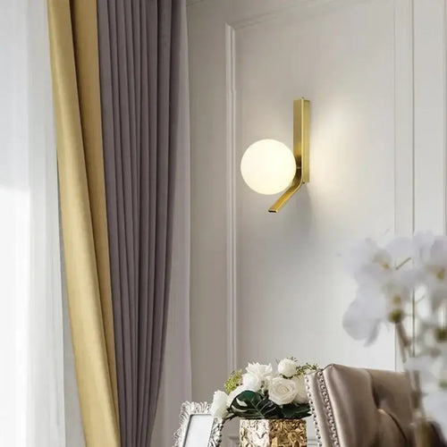 Contemporary Golden Wall Lamp with Glass Ball illuminating a modern living space decor.