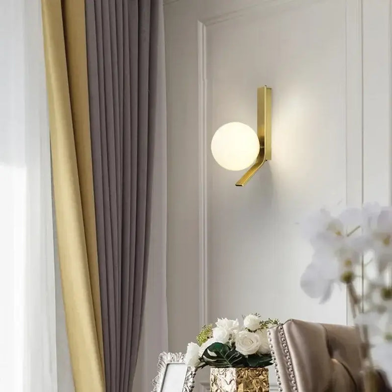 Contemporary Golden Wall Lamp with Glass Ball illuminating a modern living space decor.
