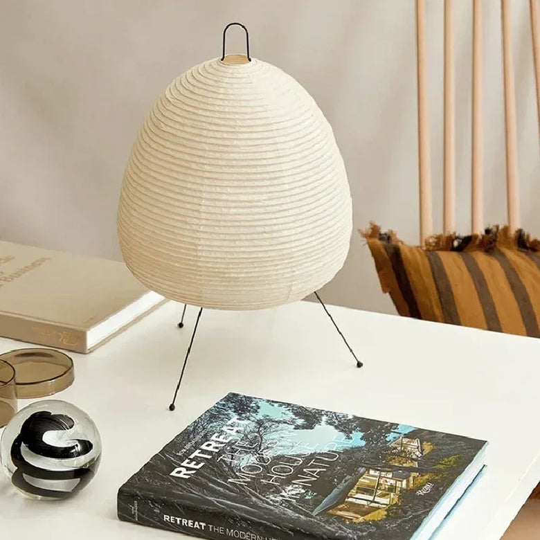Japanese Rice Paper Lamp. White textured table lamp on a surface with books and decor items.
