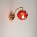Colourful Glass Modern Wall Light with a golden base and a vibrant red bulb, perfect for modern decor.
