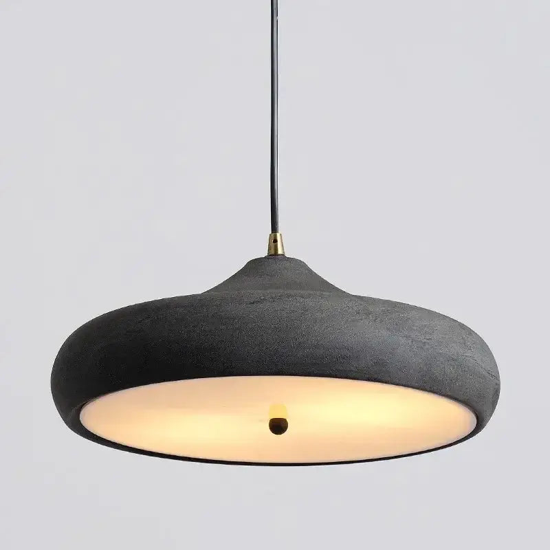 Hero Black pendant light with a warm glow on a gray background