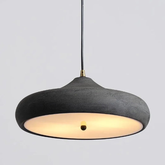 Hero Black pendant light with a warm glow on a gray background