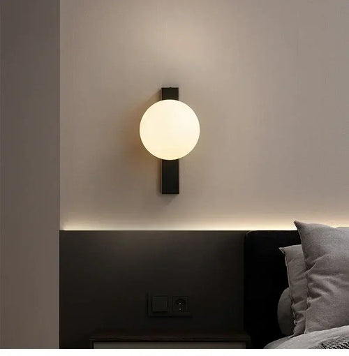 Minimalist Nordic Wall Lamp with Frosted White Ball illuminated on a modern bedroom wall.