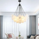 Contemporary Frosted Glass Ball & Gold Chain Chandelier in a modern living room with stylish decor.