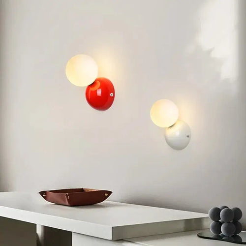 70s revival wall lamp in 3 different colours mounted on a wall, featuring a painted metal base and frosted glass balls.