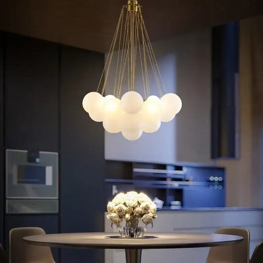 Contemporary Frosted Glass Ball & Gold Chain Chandelier illuminating a modern dining area with elegant design.