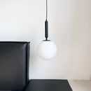 Modern Gold Glass Ball Pendant with black metal and white glass lampshade in a stylish interior setting.