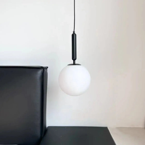 Modern Gold Glass Ball Pendant with black metal and white glass lampshade in a stylish interior setting.