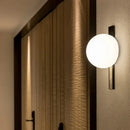 Decorative Lighting Fixture With Milk White Glass Sphere mounted on a wall, featuring a sleek black design and ambient glow.