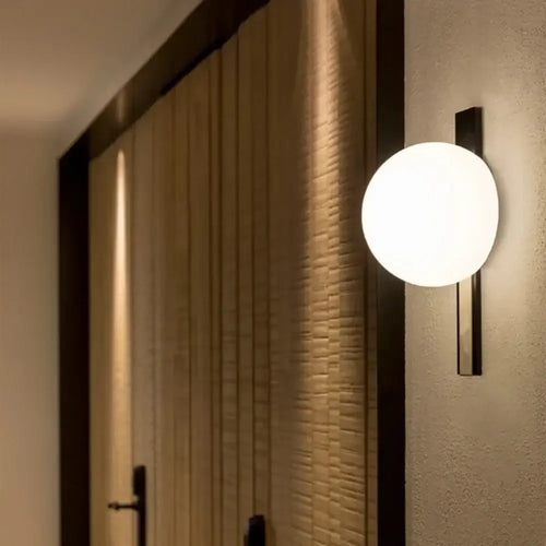 Decorative Lighting Fixture With Milk White Glass Sphere mounted on a wall, featuring a sleek black design and ambient glow.