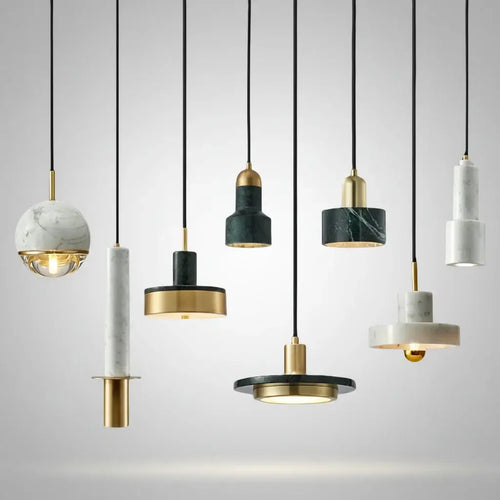 Hero A set of modern pendant lights with black cords, featuring marble and dark green stone cylindrical and spherical shades with gold metal accents, shown against a plain white background.