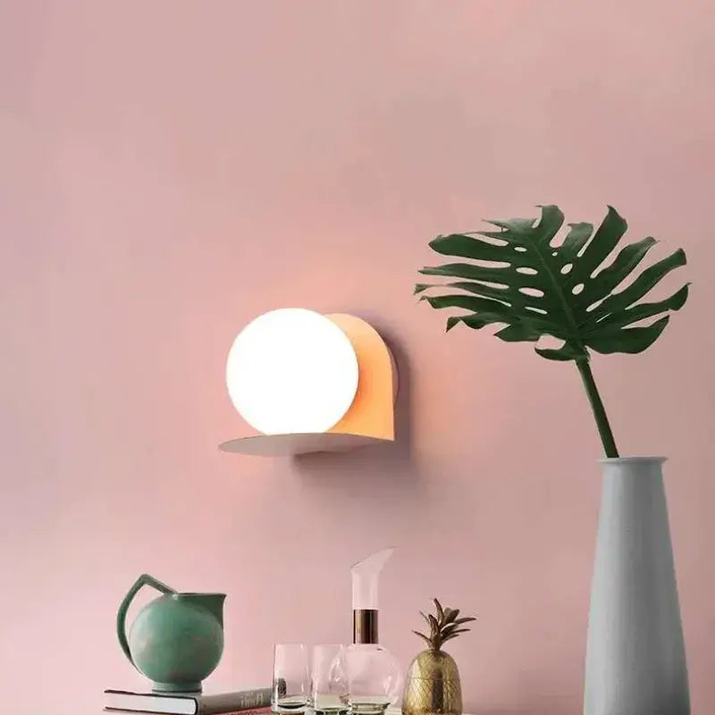 Chic Modern Sconce Collection – Illuminate with Style featuring a stylish round wall light against a pink backdrop.