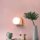 Chic Modern Sconce Collection – Illuminate with Style featuring a stylish round wall light against a pink backdrop.