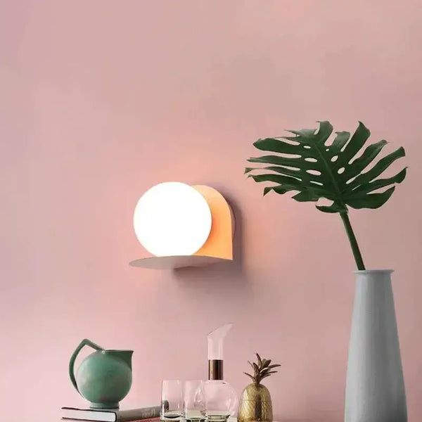 Chic Modern Sconce Collection – Illuminate with Style featuring a stylish round wall light against a pink backdrop.