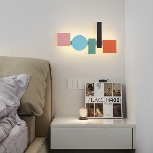 Multicolour Wall Totem LED geometric light illuminating a cozy bedside table with books and decor.