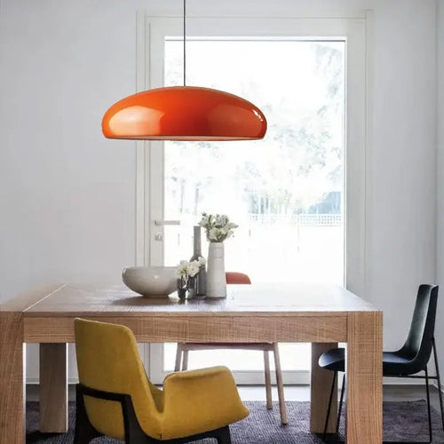 Simple Hanging Lamp in modern dining area with orange shade and wooden table.