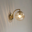 Colourful Glass Modern Wall Light with golden metal base and transparent bulb illuminating a wall.