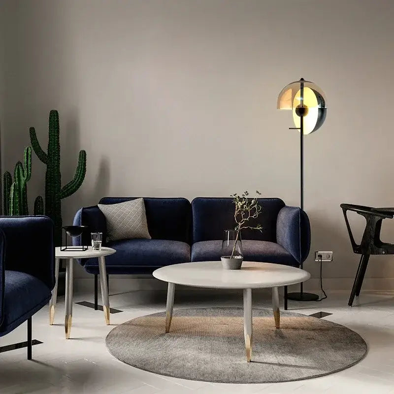 Modern living room with a blue sofa, round coffee table, and decorative elements.